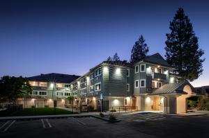 a blue green apartment building with white trim lit up in the early hours of dusk