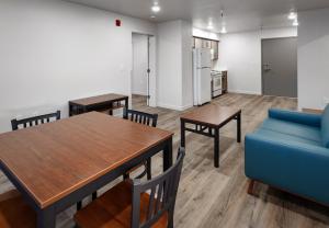 a view inside an apartment with white walls, wood floors, brown desk, brown kitchen table, brown coffee table, and blue sofa