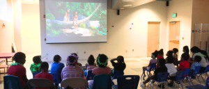 Children watching an animated film in a dimmed room.