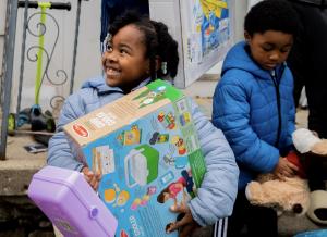 A young girl smiles as she holds gifts