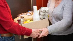 Nurse handing groceries to an older lady