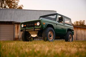 Ford Eruption Green Electric-Powered 1977 Early Ford Bronco in a field in front of a barn