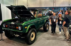 A fully electric 1977 Ford Bronco built by Kincer Chassis, displayed at the SEMA 2024 event with its hood open, revealing the electric powertrain.