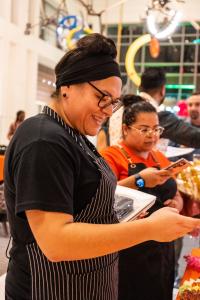 Head Chef Cristina Sanchez and Sous Chef Heidi Pelen photographing the stunning food display prepared for the Diwali celebration at Arbol Eatery, featuring vibrant dishes inspired by Indian and global cuisines.