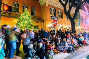 A crowd of people are viewing a large Christmas tree in Kennett Square at the Holiday Light Parade.