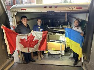 Mriya Aid volunteers with Canadian and Ukrainian flags in front of delivery truck