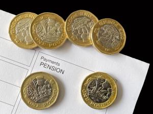 Close up view of one pound coins on top of an anonymous pension payment slip