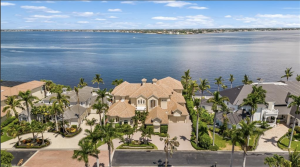 This waterfront home offers multiple covered and open outdoor spaces, private elevator, pool and spa, rock waterfall, outdoor kitchen, seating with fireplace, pool bath with steam room, and a lounging deck.