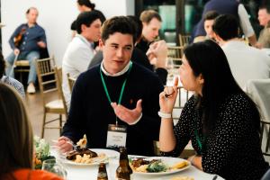 Two people are having a conversation over dinner in a room of investors, founders, and ecosystem supporters.