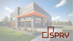 Exterior view of the new SPRY Manufacturing facility, featuring a modern design with a prominent orange accent and the SPRY logo in burgundy.
