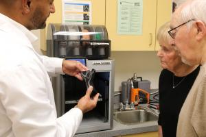 This image depicts a doctor showing a patient the new personalized medical device option for custom-fit, 3D printed devices using the on-site, XO Armor printer.