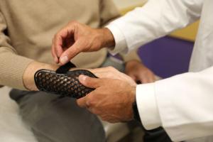 This image depicts a doctor fitting a customized medical device onto the hand of a patient