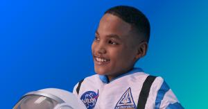 a boy dressed in an astronaut suit looks up to the sky