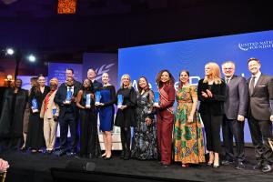 Un grupo de líderes mundiales, agentes de cambio y visionarios de pie en el escenario durante la Gala We The Peoples de la Fundación de la ONU, simbolizando la unidad y el compromiso compartido con los objetivos de desarrollo sostenible.