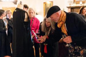 Guests examine the construction techniques of a 1950s Balenciaga haute couture dress turned inside out, using magnifying glasses to study its craftsmanship.