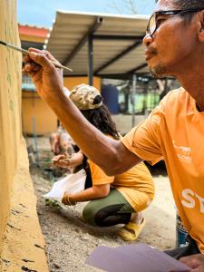 The Man That Rescues Dogs staff paint the names of 100 book readers onto the wall at the Sanctuary