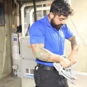 J. Blanton Plumbing technician repairing a residential water heater, showcasing the company's expertise in 24-hour plumbing service and water heater repair for cold weather preparation.