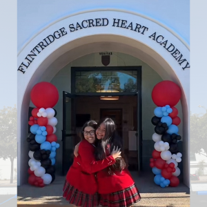 Two Flintridge Sacred Heart Academy students hug and smile in front of the new signage on the archway of the newly renovated high school building.