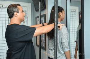 Dr. John Gehnrich Performing an Examination, he is standing behind his patient