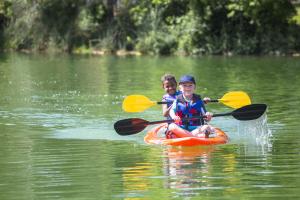 two boys kayak on lake at summer camp