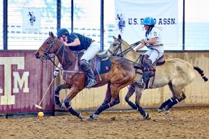 Two arena polo players on horses go for goal