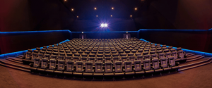 Empty cinema hall with rows of grey seats and blue accent lighting.