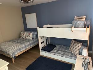 A renovated bedroom featuring a bunk bed and a twin bed with clean, modern furnishings, offering a comfortable and functional living space for families at Thomas House Family Shelter. Bathroom and walk-in closet not pictured.