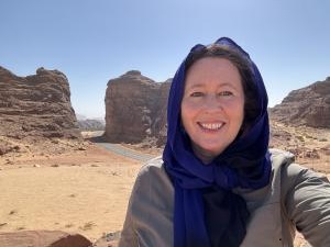 Explorer Alice Morrison standing in front of a large rock formation in AlUla, Saudi Arabia