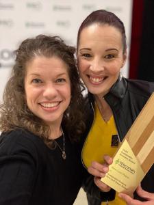 Shannon Bone, President of New Leaf Paper, and Sabrina Schwietzer, VP of Retail Marketing & Sales, smiling while holding the 2024 Sustainable Product Award for New Leaf Green Notes™, recognizing their eco-friendly innovation.