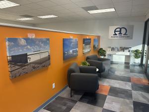 New office lobby with two chairs, pictures on the wall, and a table with magazines.