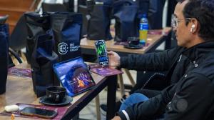 Two traders check stock indexes on their phones, with EBC merchandise on the table, at the LATAM Traders’ Exchange event in Colombia - EBC