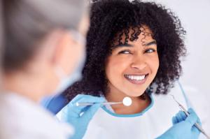 A female client with curly hair confidently smiles, revealing her bright pearly white teeth during a general dentistry appointment.