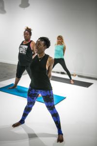 Pilates and yoga instructor Ivory Howard teaching wide legged forward fold pose in a yoga class.