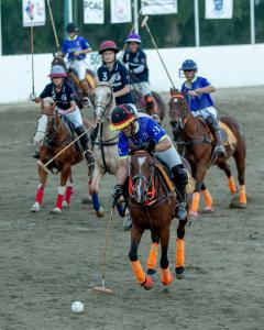 several arena polo players ride behind a player carrying the ball to goal