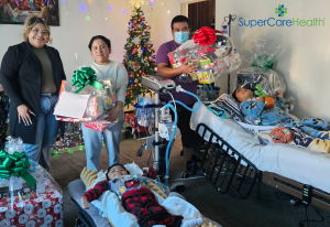 Parents receive donated holiday gifts for chronically ill children in living room decorated for Christmas