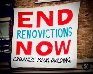 A white bedsheet is hung from the metal balcony of a building, written on it in red and blue paint are the words 'END RENOVICTIONS NOW' 'Organize Your Building Now'. Its a protest banner hung from abuilding balcony protesting illegal evictions and specifi