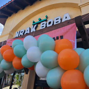 Storefront of a Krak Boba with signs and a balloon archway