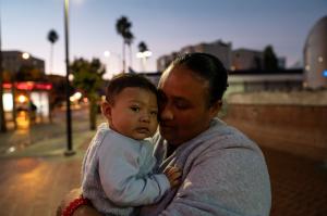 A mother holds her son in the early morning hours after leaving a shelter for unhoused residents that operates as a K-8 school by day.