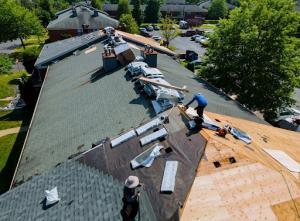 A worker providing professional roofing services while installing new shingles on a house during a renovation project.