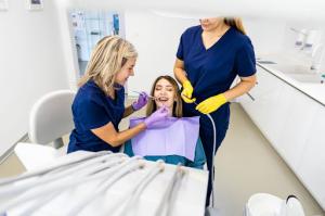 A female patient getting dental work done by two female professionals.