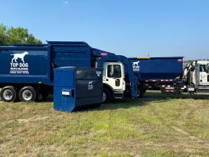 Top Dog Waste Solutions' blue dumpster and fleet of trucks parked, prepared for efficient food waste collection and management services.