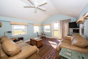 Inside Michener's Beach Cottage Cabana with leather coaches and several waterfront windows