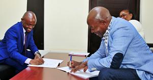 Benvictor Makau (left) and Dr. Charles Nzivo sign an MoU between The Trueness Project and the Kenya National Library Service. Photo by Godfrey Atsing'a, The Trueness Project.