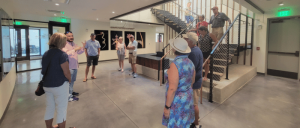 Group of people standing in a modern lobby with a staircase.