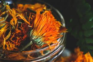 Close-up detailed image of dried calendula (Calendula officinalis) flowers in a glass jar.