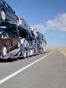 An open auto transport on a highway loaded with cars