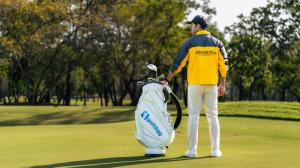 "A golfer in an AIRPORTELs uniform standing on a golf course next to a Golfdigg-branded golf bag, showcasing the convenience of seamless golf bag delivery services in Thailand."