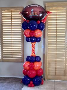 A festive balloon tower celebrating Super Bowl LIX in New Orleans, featuring a 22-inch football-shaped Anagram foil balloon with the Super Bowl 59 LIX NFL logo at the top, adorned in the official Super Bowl colors of orange and red