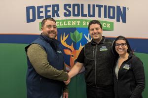 Nick Bradley, left, shakes hands with co-founders of Deer Solution Kris Goodrich, center, and Jaime Goodrich, right.