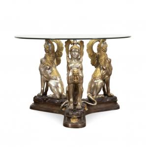 Egyptian Revival style glass top and sphinx base center table having a silvered and gilt bronze base supporting a round glass top, unmarked, 28 ¾ inches tall and 42 inches in diameter ($10,890).